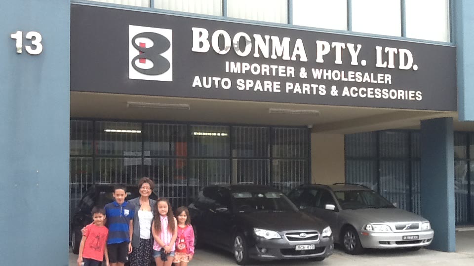 Boonma outside our current warehouse in Lansvale with her grandkids, under our original sign